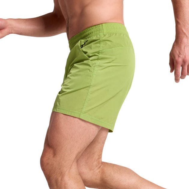 A person is wearing lime green shorts with an elastic waistband and side pockets.
