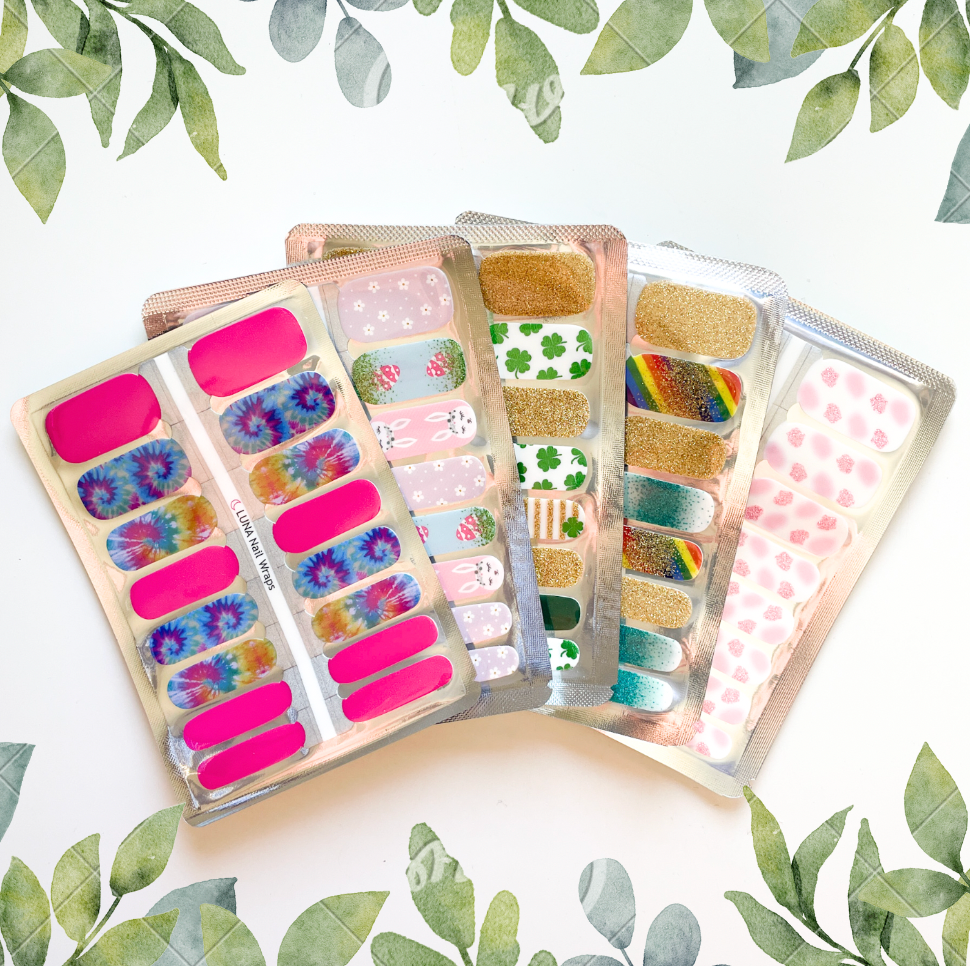 Assorted nail polish strips with various designs and colors, including pink, gold, patterned, and seasonal themes, displayed on a white background with green leaves.
