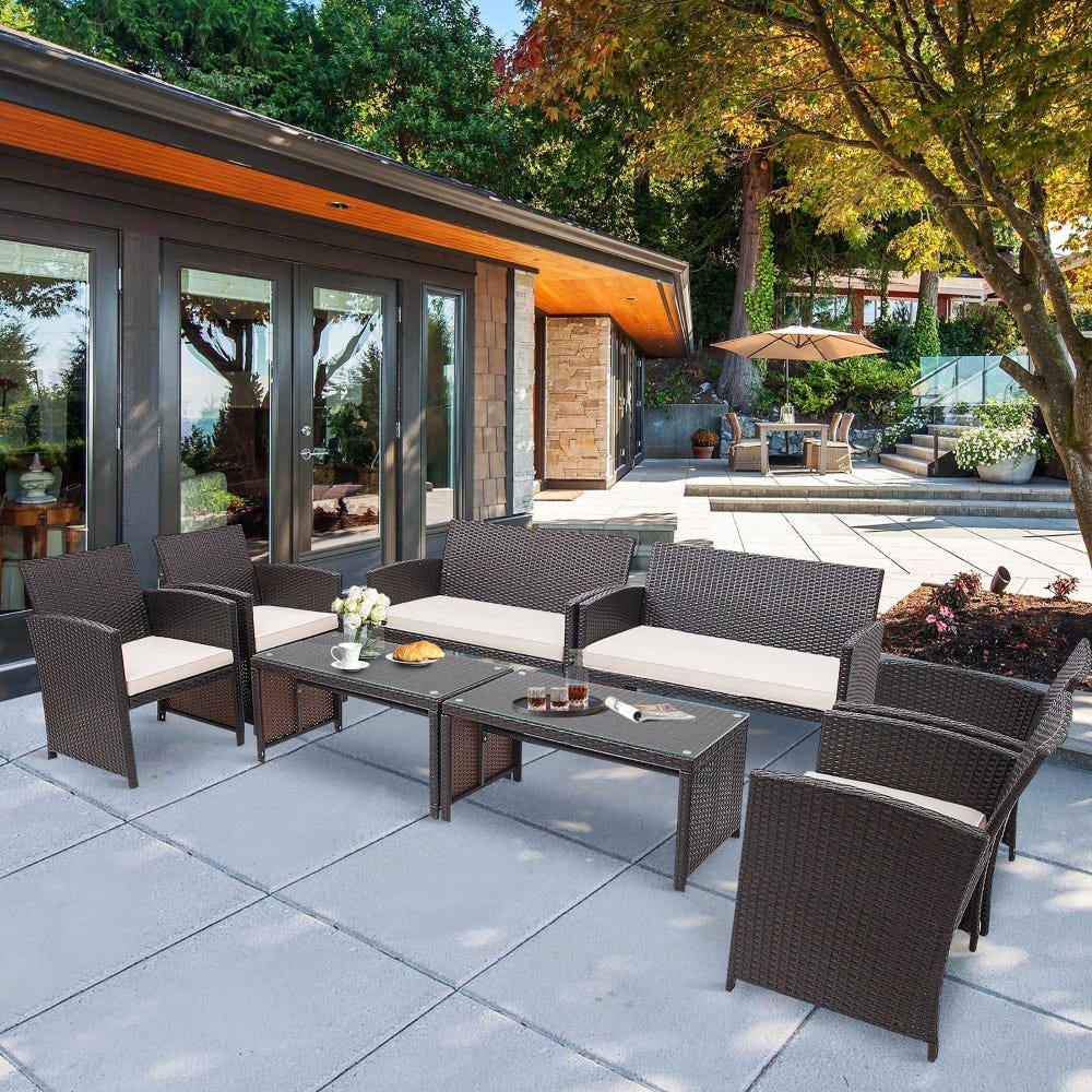 Wicker outdoor furniture set with cushions, a glass-topped coffee table, and coordinating side chairs.
