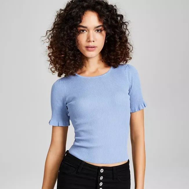 A woman wearing a blue ribbed crew-neck crop top and high-waisted black jeans.