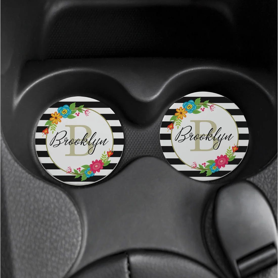 Personalized coasters feature black and white stripes with floral accents around the name \“Brooklyn\“ and the letter \“B\“ in the center. They are designed to fit in car cup holders or for desk use.