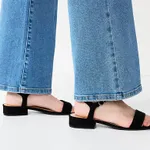 Light wash high-waisted jeans with a straight leg cut, paired with black open-toe sandals.