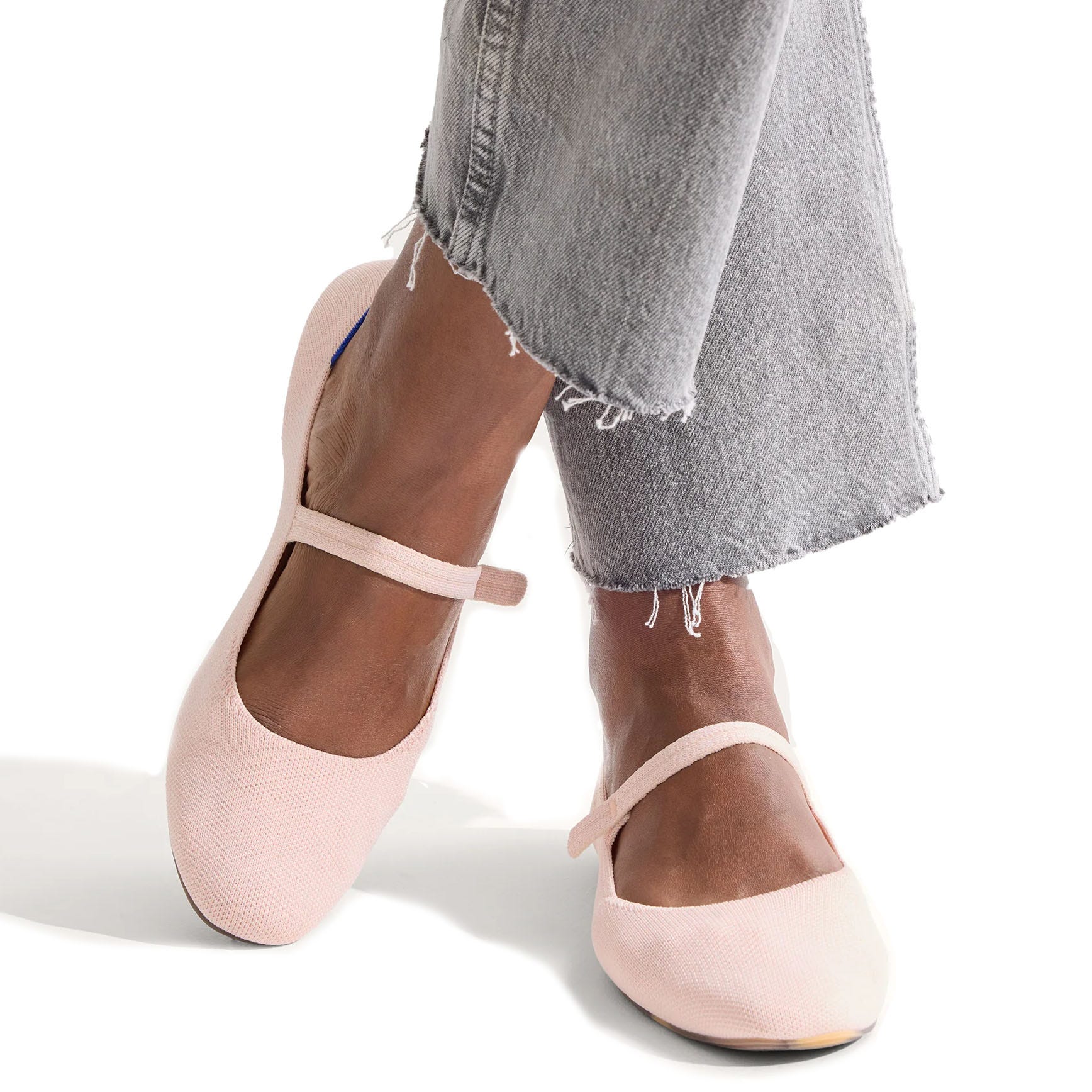 Light pink Mary Jane flats paired with frayed hem gray jeans.