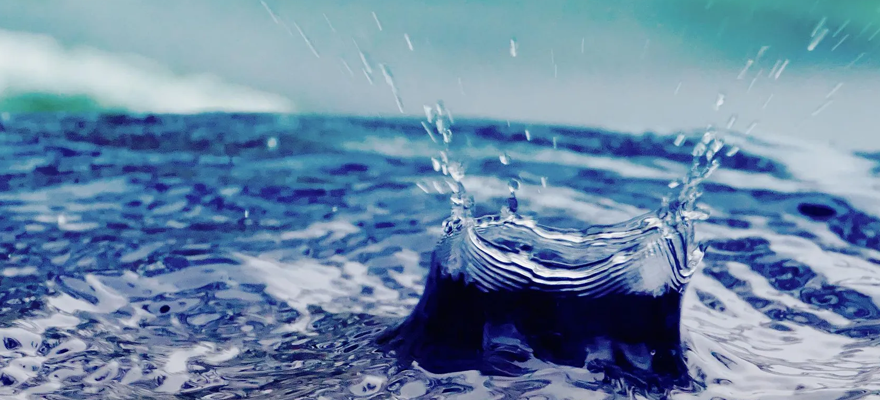 A drop of water falls into a rain barrel.