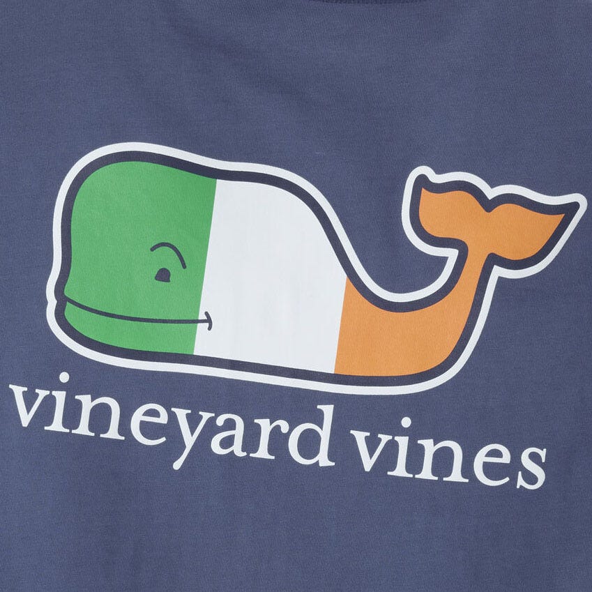 Navy blue tee featuring a whale graphic colored with the Irish flag's green, white, and orange stripes, above the text \“vineyard vines.\“