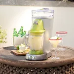 A Margaritaville Drink Maker with a large ice reservoir and blending jar, displayed on a wooden surface alongside lime slices and two prepared margaritas.