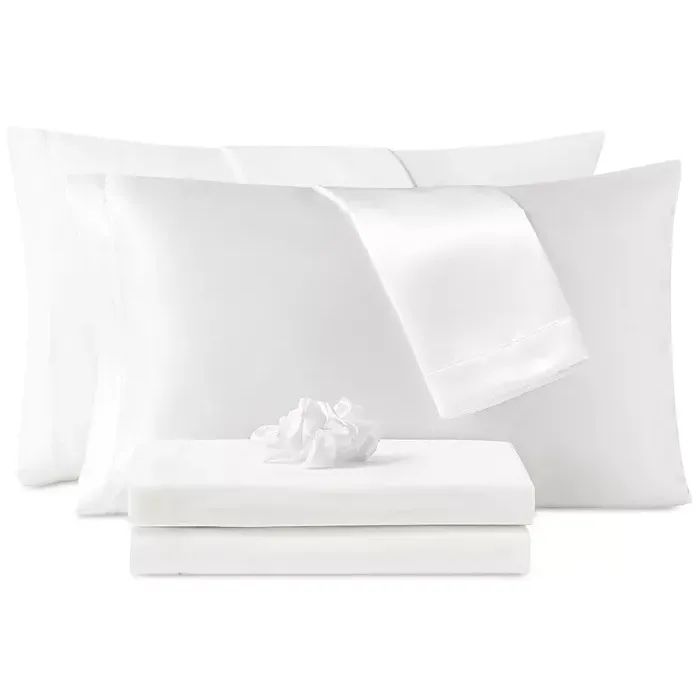 White bed sheets set that includes a fitted sheet, flat sheet, pillowcases, and a decorative crumpled fabric accent.