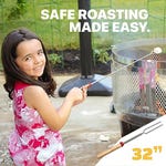 A young girl smiles while using an expandable 32-inch s'mores stick to roast a marshmallow over a fire pit.