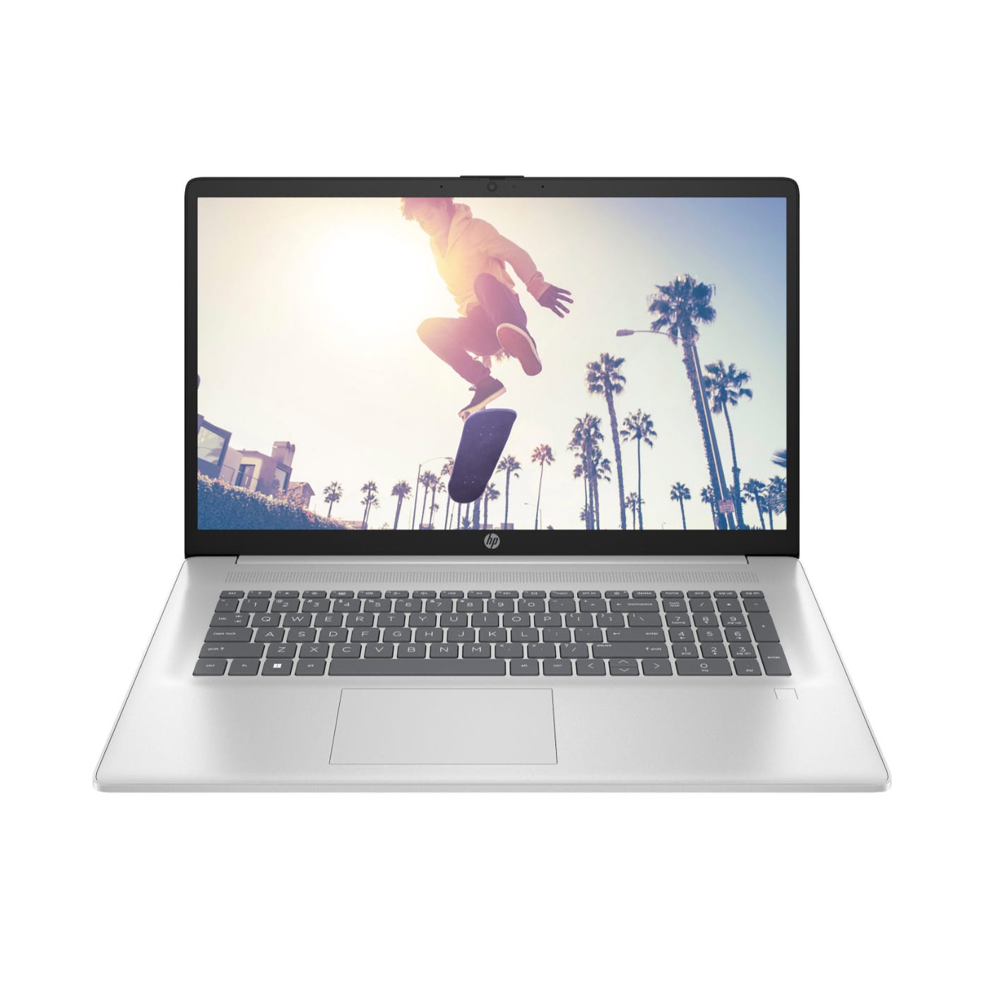 A silver HP laptop is open, displaying an image of a skateboarder performing a trick with palm trees in the background.