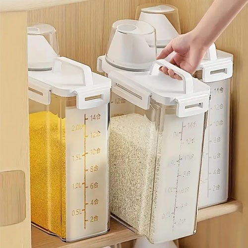 A hand is opening a transparent food storage container with measurement markings that hold pasta and rice.