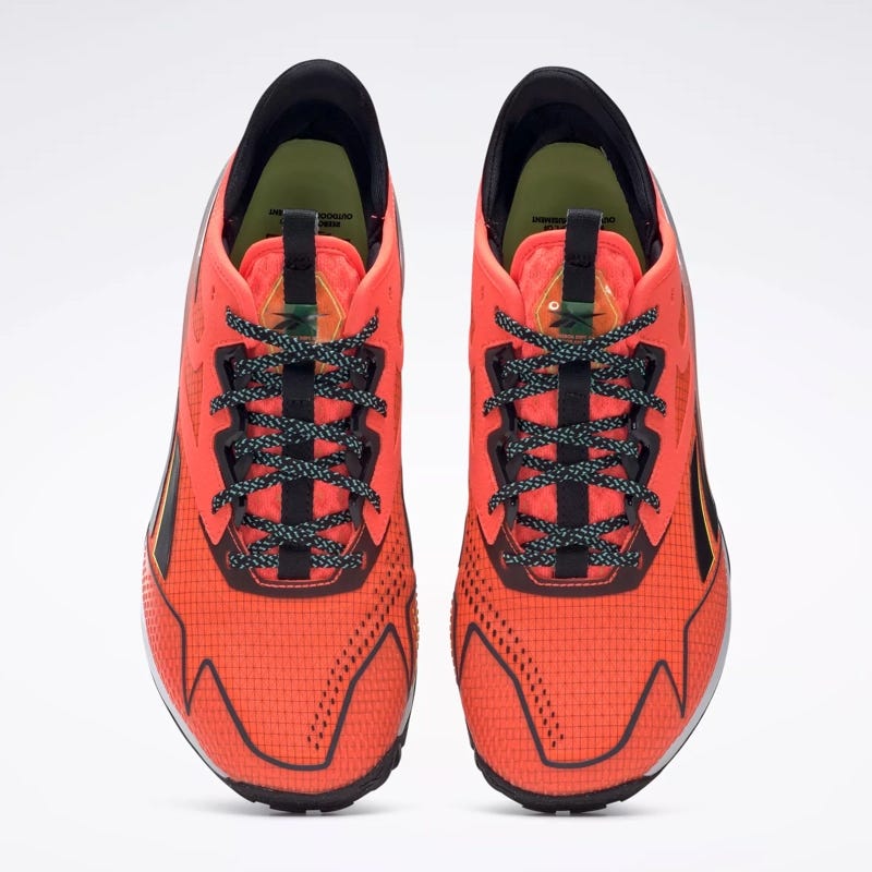 A pair of bright orange running shoes with black laces and detailing.