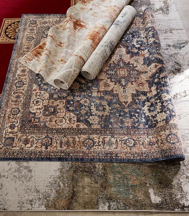 Several rolled and partially unrolled ornate area rugs are displayed on a floor.