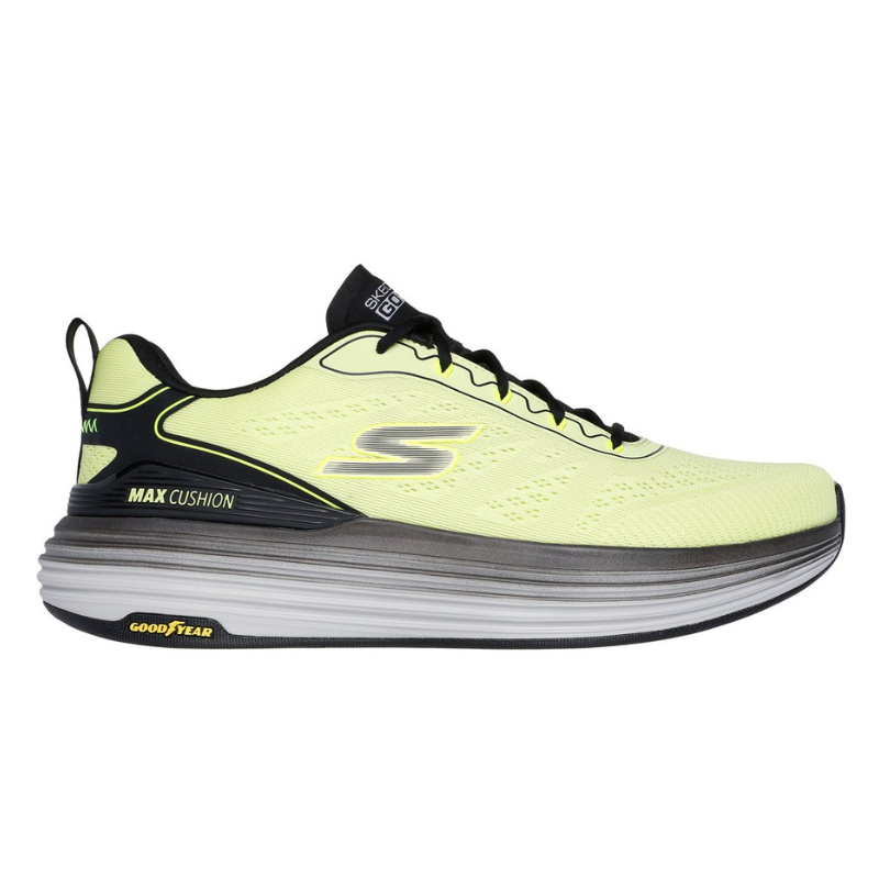 Bright yellow athletic shoe with black accents, featuring a thick, cushioned sole labeled \“MAX CUSHION\“ and a Goodyear outsole. The shoe has a sleek design with a logo on the side and pull tabs on the heel.