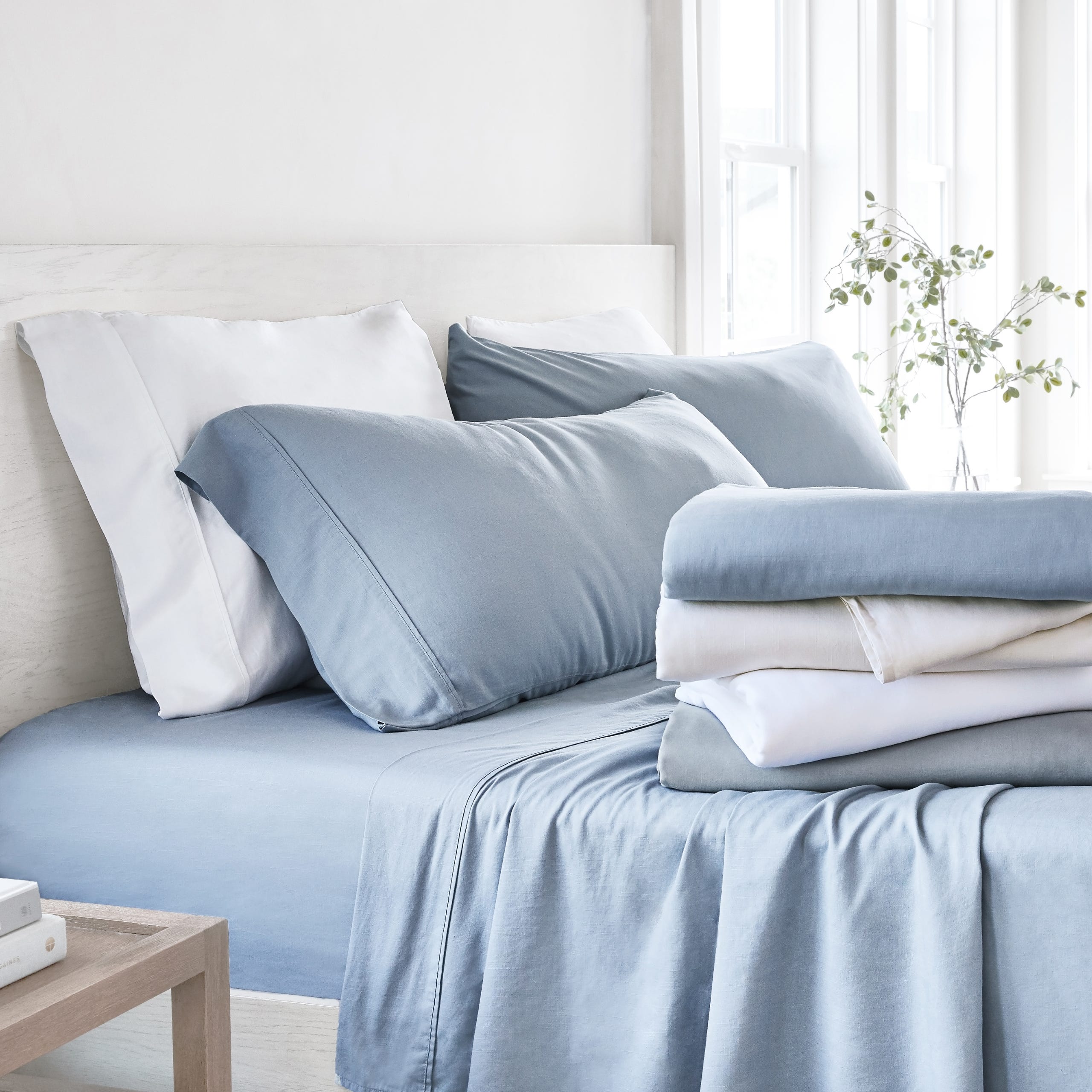 A neatly made bed with blue and white bedding, including pillows, sheets, and duvet covers.