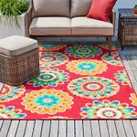 A colorful outdoor rug with a floral pattern, displayed under patio furniture on a wooden deck.