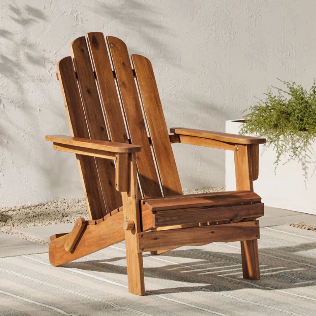 The Blackwell Adirondack Chair features a classic slatted design in natural wood tones, suitable for outdoor settings. Its sturdy construction includes wide armrests and a gently reclined back for comfort.