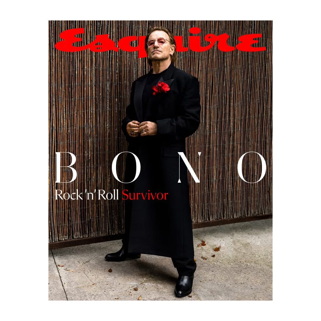 A black-clad figure with a red flower boutonniere stands confidently on the cover of Esquire magazine, featuring the headline \“BONO: Rock 'n' Roll Survivor\“ in contrasting white and red text.