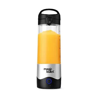 A Magic Bullet blender filled with orange liquid, featuring a black lid with a handle, a white body with volume measurement marks, a prominent brand logo, and a blue power button at the base.