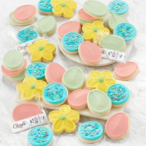 Colorful iced cookies in flower and egg shapes, packaged individually with a brand label.