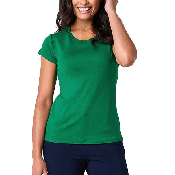A woman is wearing a green short-sleeve T-shirt paired with dark pants. She is smiling and wearing her hair down.