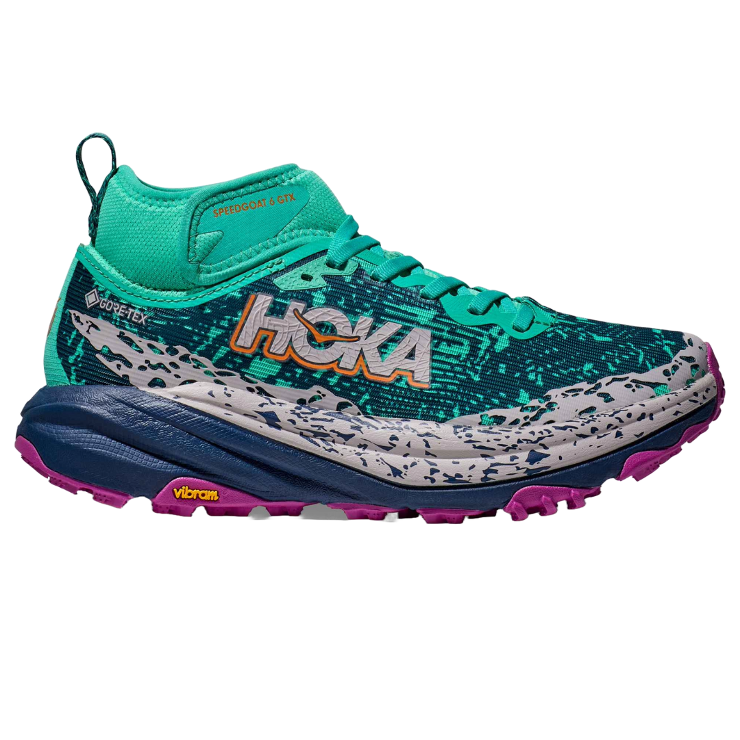 A teal Hoka Speedgoat 6 GTX trail running shoe features Gore-Tex material, a Vibram sole, and a colorful design with white speckles and pink accents.