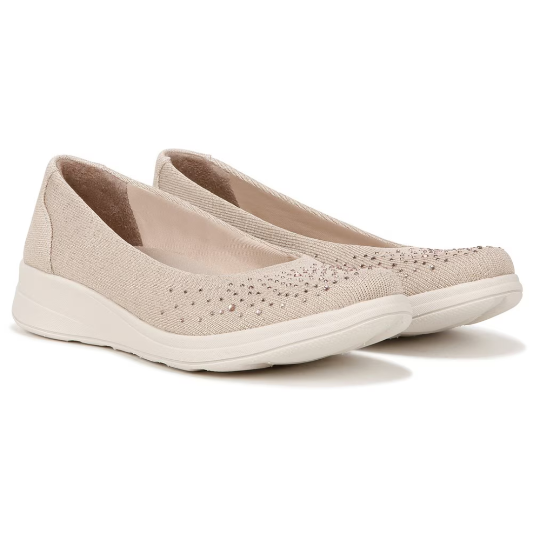 A pair of beige slip-on shoes with decorative perforations and a white sole.