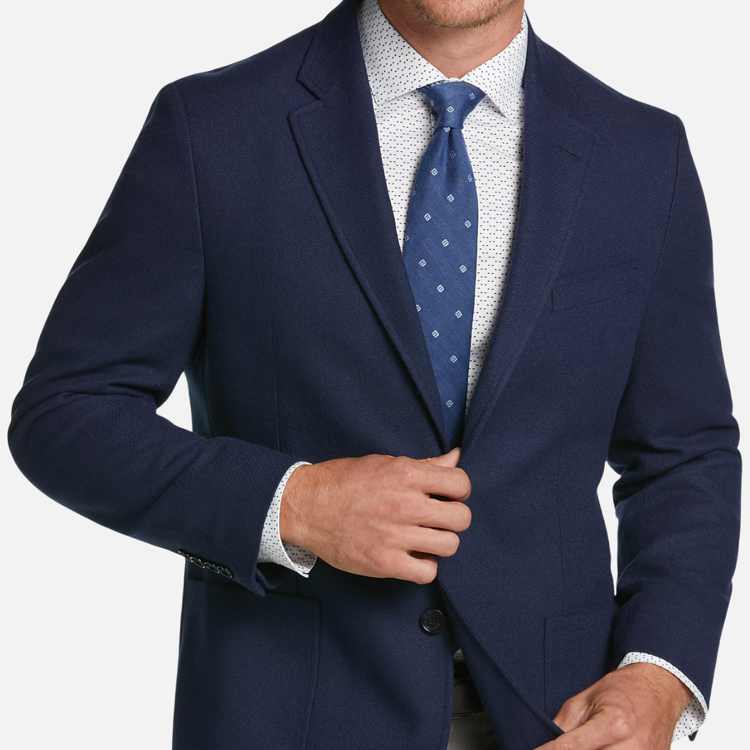 Navy suit jacket, blue tie with patterns, and a white dotted shirt.