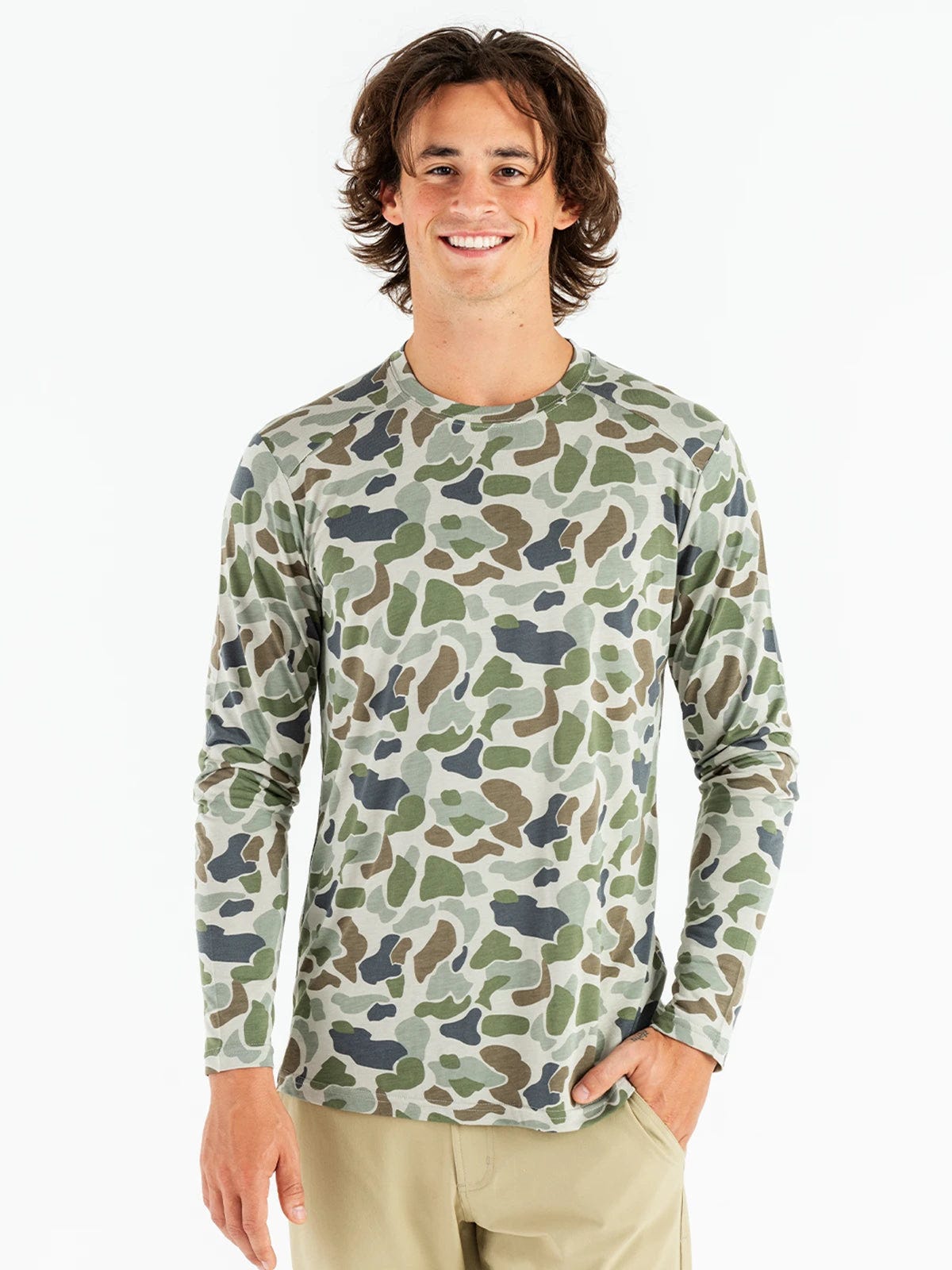 A man is wearing a long sleeve bamboo shirt with a camo pattern in shades of green, beige, and navy.