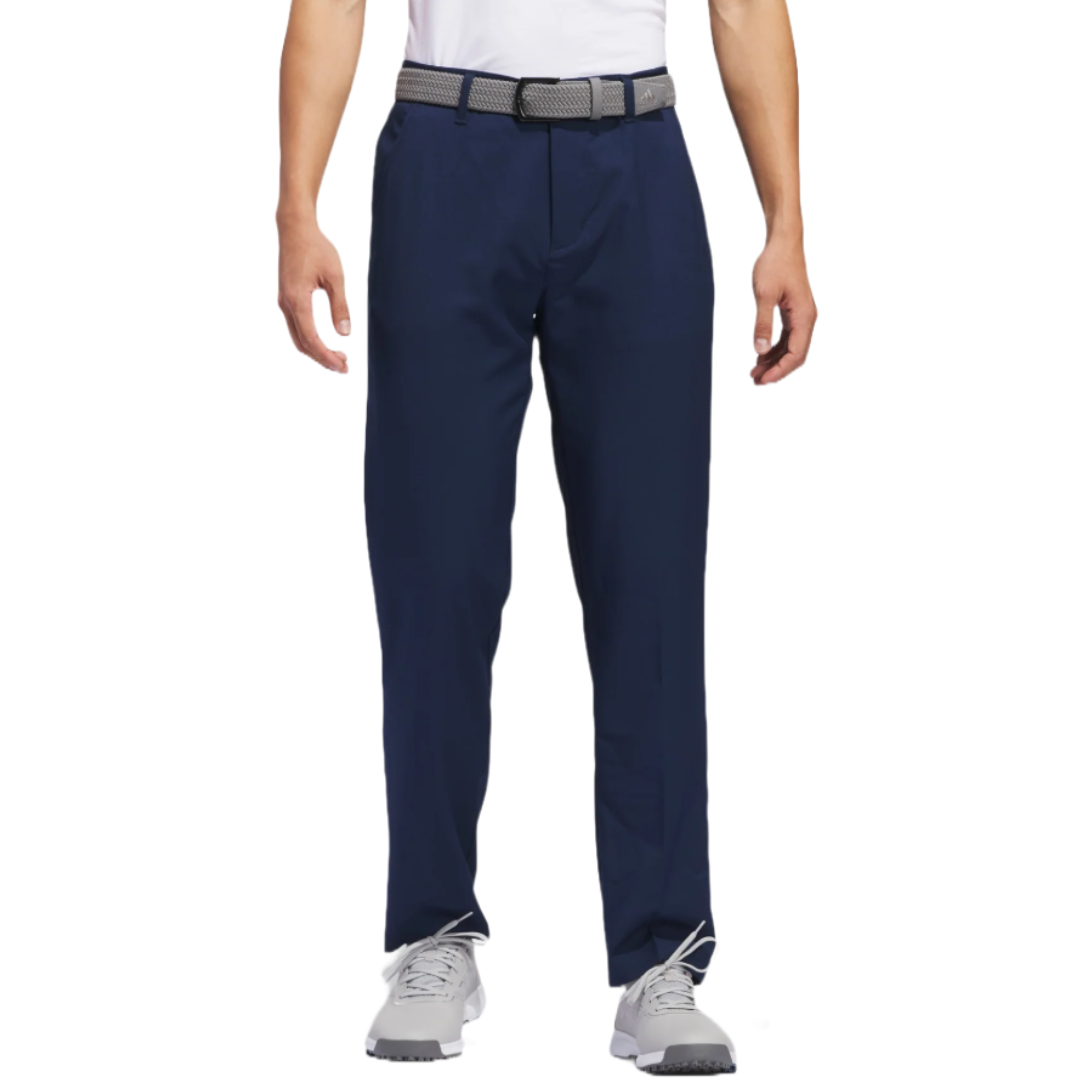 A man is wearing navy blue trousers with a gray belt, paired with a white shirt and gray sneakers.