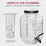 A glass drink dispenser with an embossed design and spigot, accompanied by an acrylic ice cylinder for chilling.