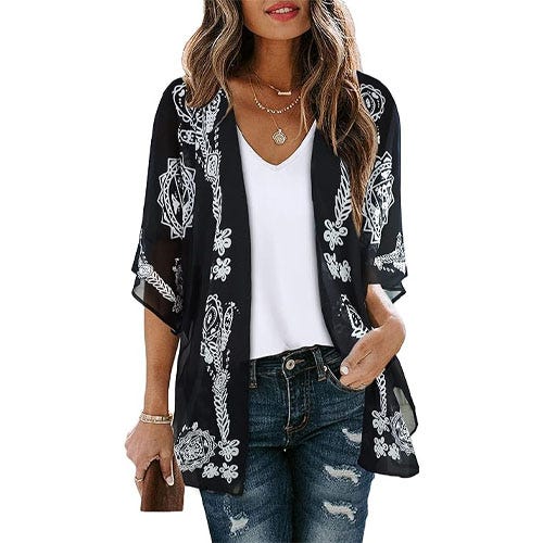 A women wearing jeans, a white tee shirt, and a flowy black and white printed cardigan.