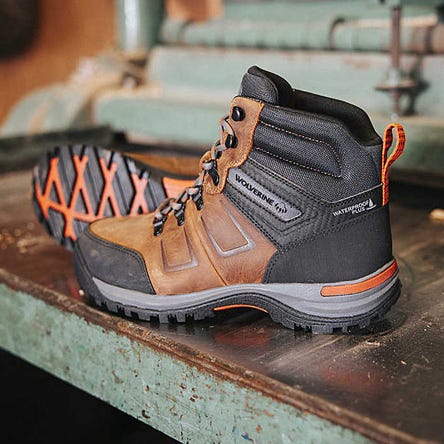 A pair of brown and black hiking boots with orange accents and waterproof labeling.