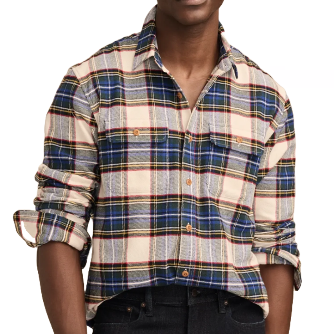 A plaid flannel shirt featuring a pattern of blue, red, and beige with button-front closure, two chest pockets, and rolled sleeves, paired with dark jeans.