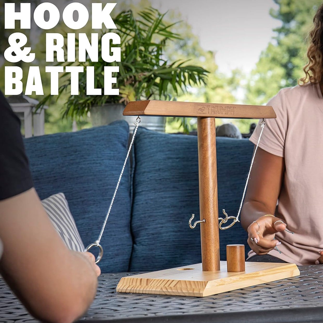 A tabletop hook and ring toss game with two players present.