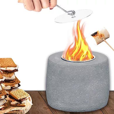 A tabletop fire pit is shown being used to roast marshmallows, with s'mores stacked nearby.
