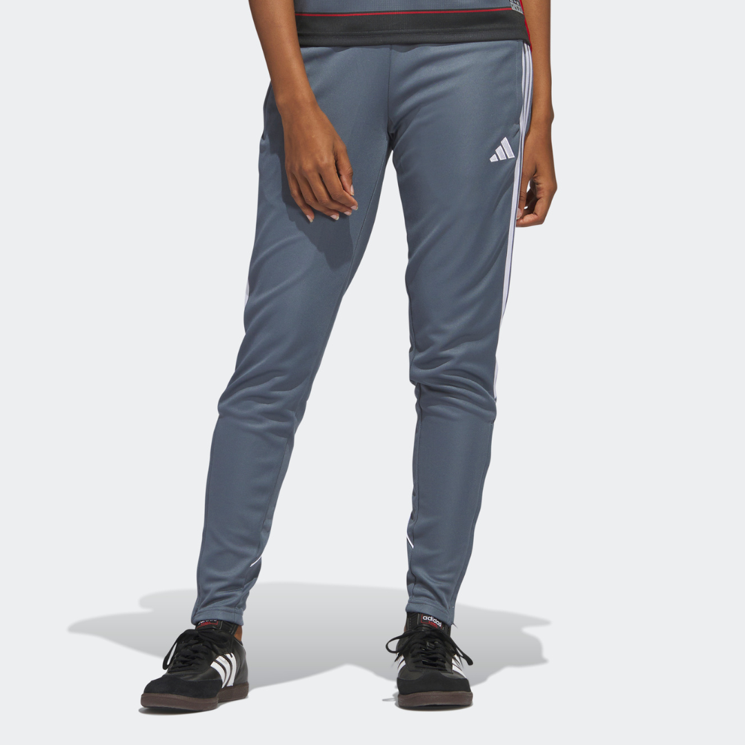 A person wearing grey Adidas track pants with a three-stripe design and black sneakers.