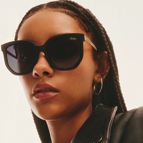 A woman wearing oversized black sunglasses and gold hoop earrings.