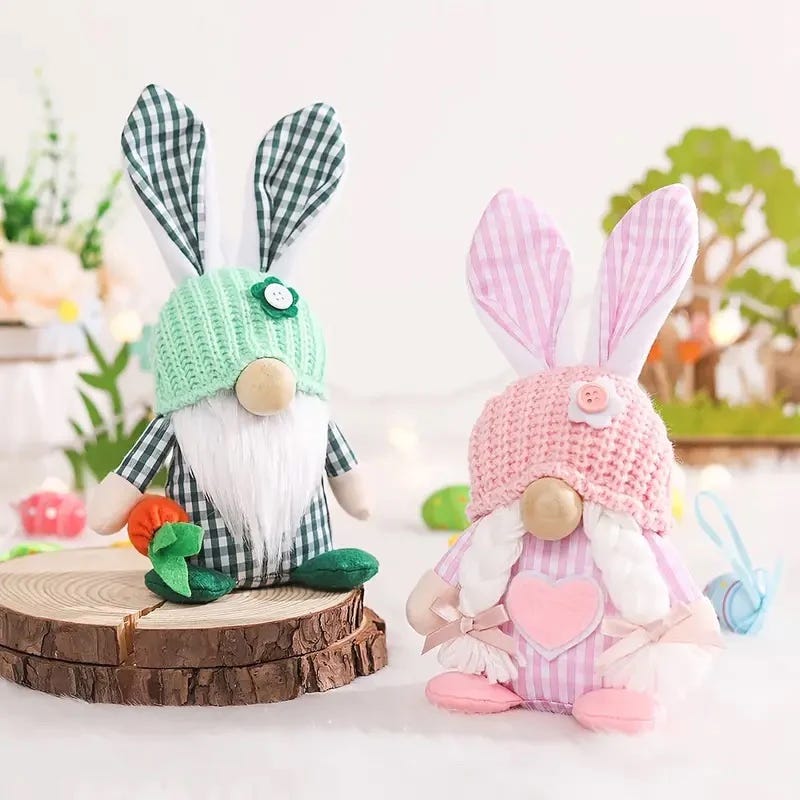 Two decorative plush bunnies with fabric details and knitted hats, one dressed in green and the other in pink.