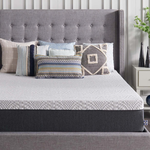 A gray upholstered bed with a diamond-patterned quilt and assorted decorative pillows in neutral and blue tones.