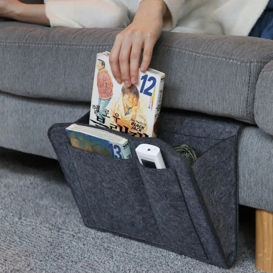 Gray felt pocket organizers hang over a sofa arm, holding books and a remote control. They're designed for convenient storage and easy access to items like magazines and gadgets.