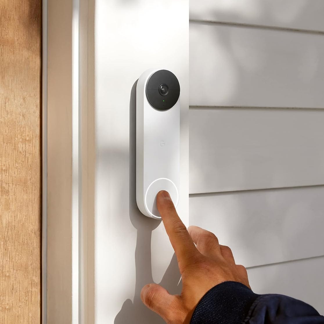 A doorbell camera with a person's finger pressing the ring button.