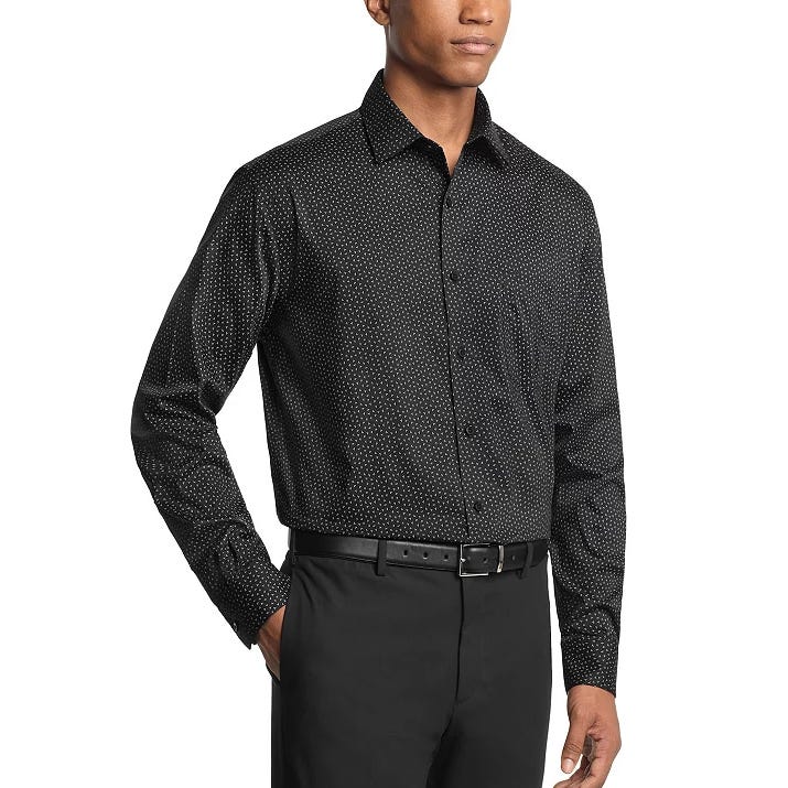 A man is wearing a black long-sleeve dress shirt with a subtle dot pattern, paired with black trousers and a black belt.