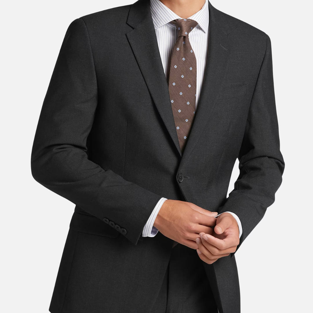 A man dressed in a dark suit, striped dress shirt, and patterned tie.