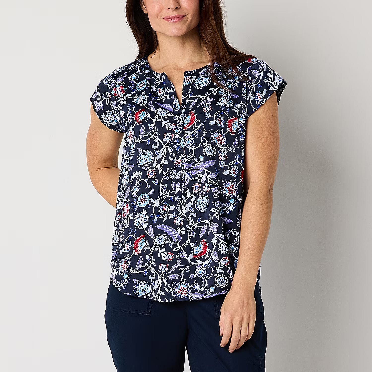 A woman is wearing a navy blue printed scrub top with a V-neck and short sleeves.