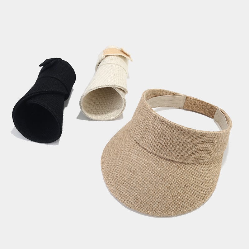 Three visor caps in beige, white, and black laid out on a neutral background.