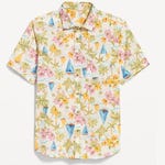A short-sleeved shirt with a tropical print featuring palm trees, flowers, and sailboats.
