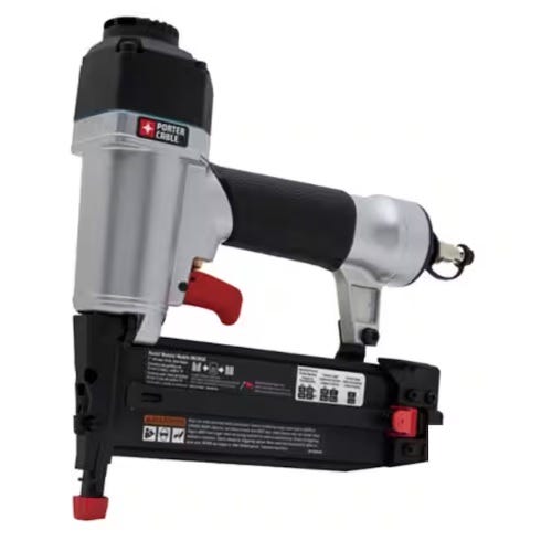 An 18-gauge pneumatic brad nailer with a metallic finish, black grip, and red trigger designed for precision nailing in woodworking projects. It features a quick-release latch for easy loading and adjustment, with an air hose connector at the rear.