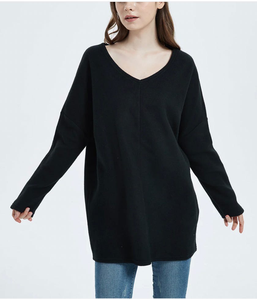 A woman wearing a black V-neck sweater and blue jeans.