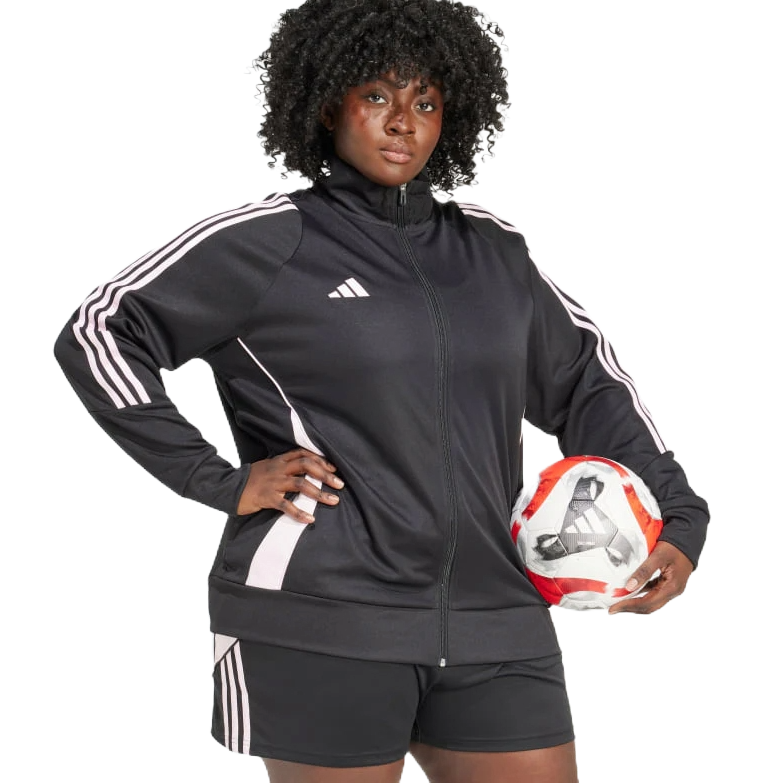 A person is wearing a black Adidas tracksuit with white stripes, holding a soccer ball. The outfit includes a zip-up jacket and shorts.