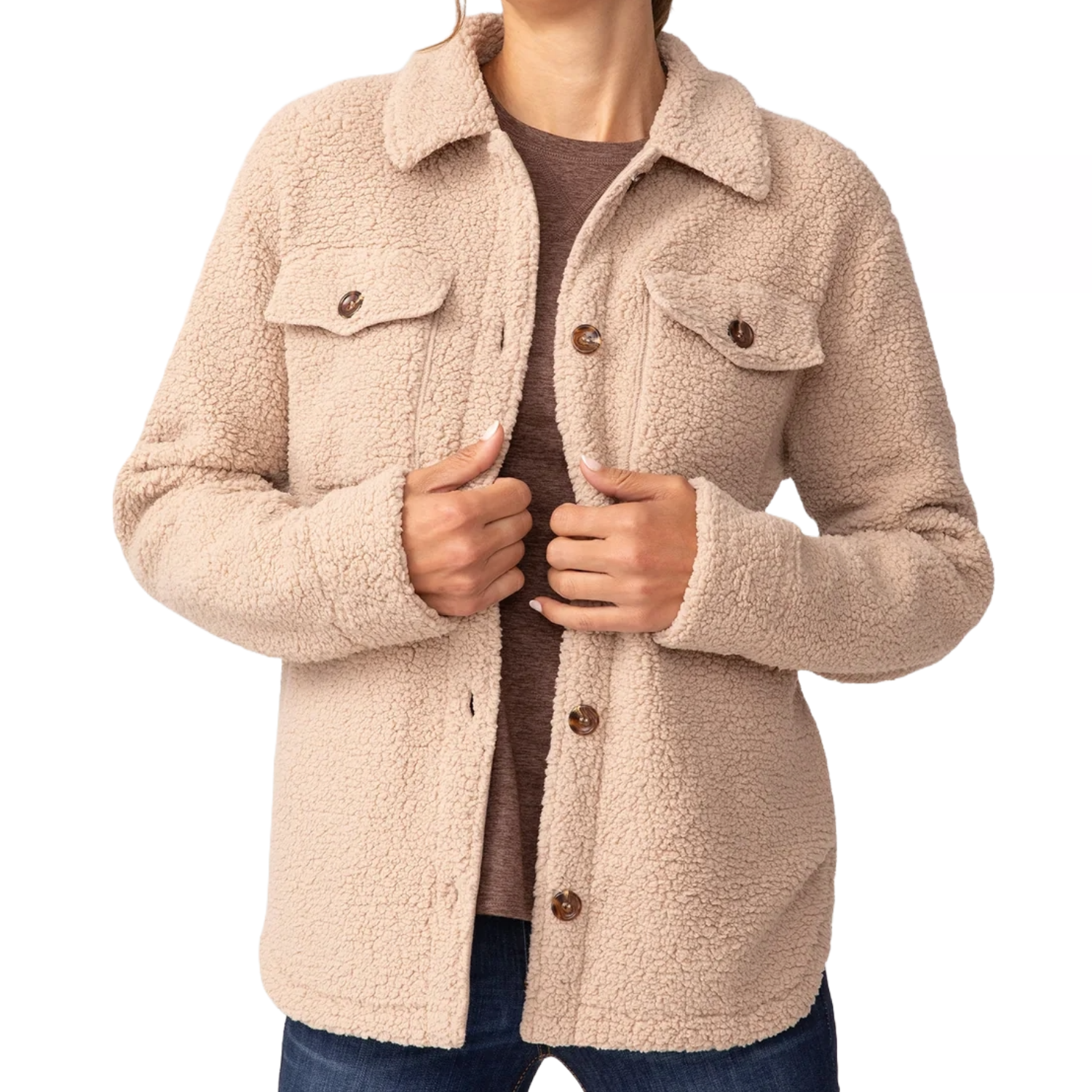 A beige sherpa shacket with a soft, fuzzy texture, featuring a collared design, button-up front, and two chest pockets with buttons. It is worn over a brown shirt and paired with jeans.